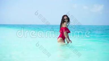 年轻漂亮的女人在干净的大海里玩绿松石水。 快乐的女孩享受热带度假的异国风情岛
